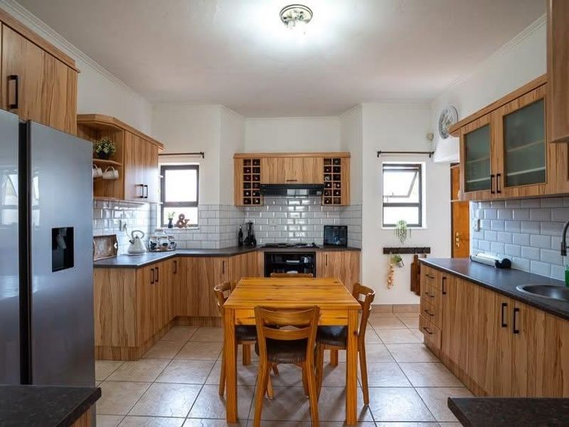 A well-maintained kitchen featuring wooden cabinetry, subway tile backsplash, dark countertops, and integrated appliances, offering a functional and classic cooking space.