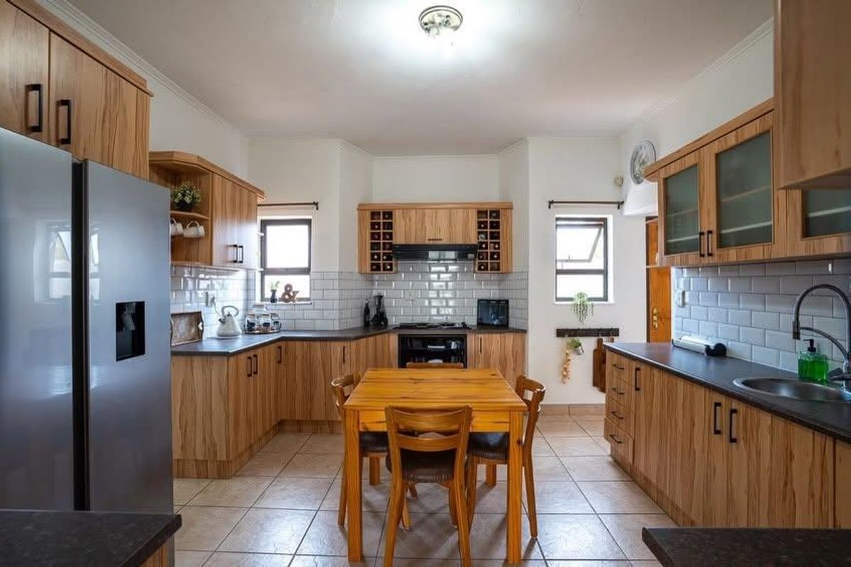 A well-maintained kitchen featuring wooden cabinetry, subway tile backsplash, dark countertops, and integrated appliances, offering a functional and classic cooking space.