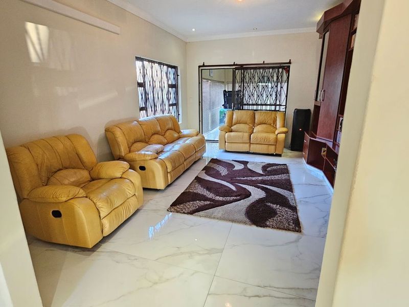 A bright living room featuring polished marble-look floor tiles, recessed lighting, and secure sliding door access to the exterior.