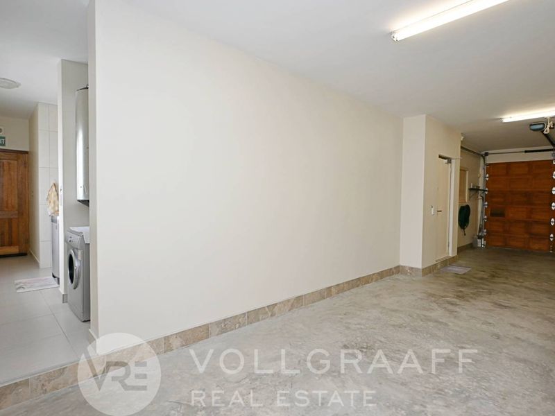 Spacious garage featuring a sectional door, fluorescent lighting, and a dedicated laundry area with plumbing connections for appliances.