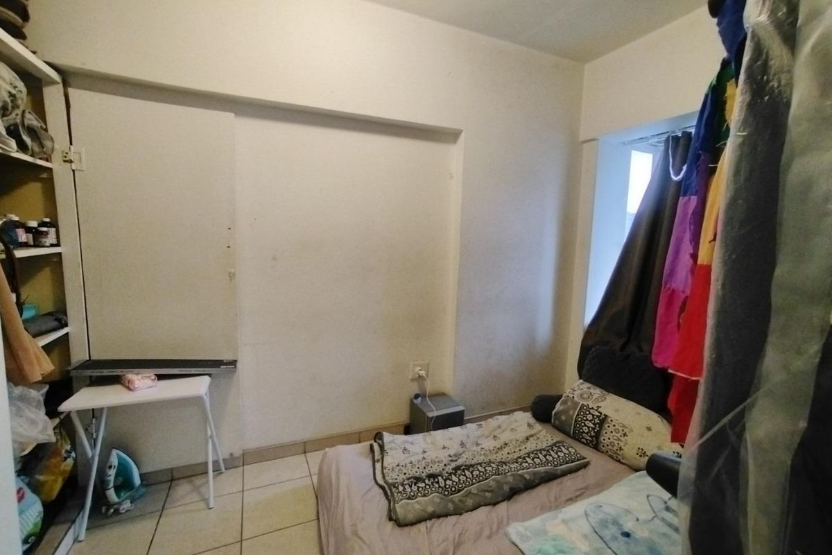 A compact bedroom featuring tiled flooring and built-in shelving, requiring cosmetic updates to improve its overall condition and appeal.