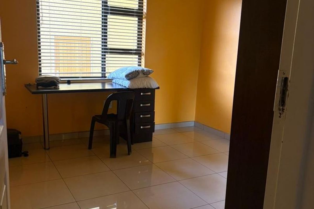 A bedroom featuring tiled flooring, bright yellow walls, and a window with fitted blinds.