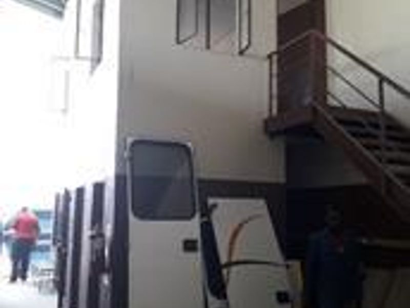 Industrial utility space featuring a mezzanine level with a metal staircase, high ceilings, and functional casement windows.