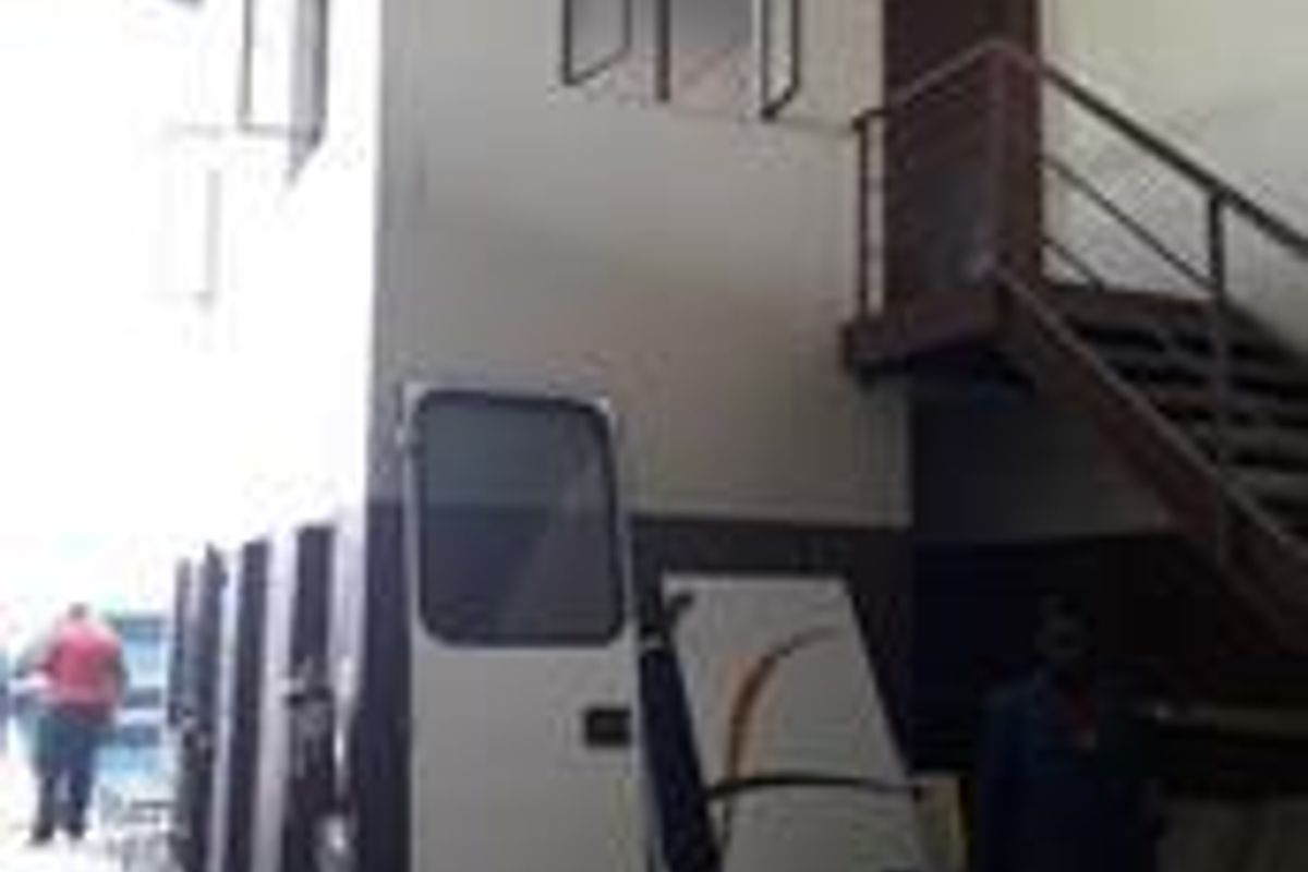 Industrial utility space featuring a mezzanine level with a metal staircase, high ceilings, and functional casement windows.