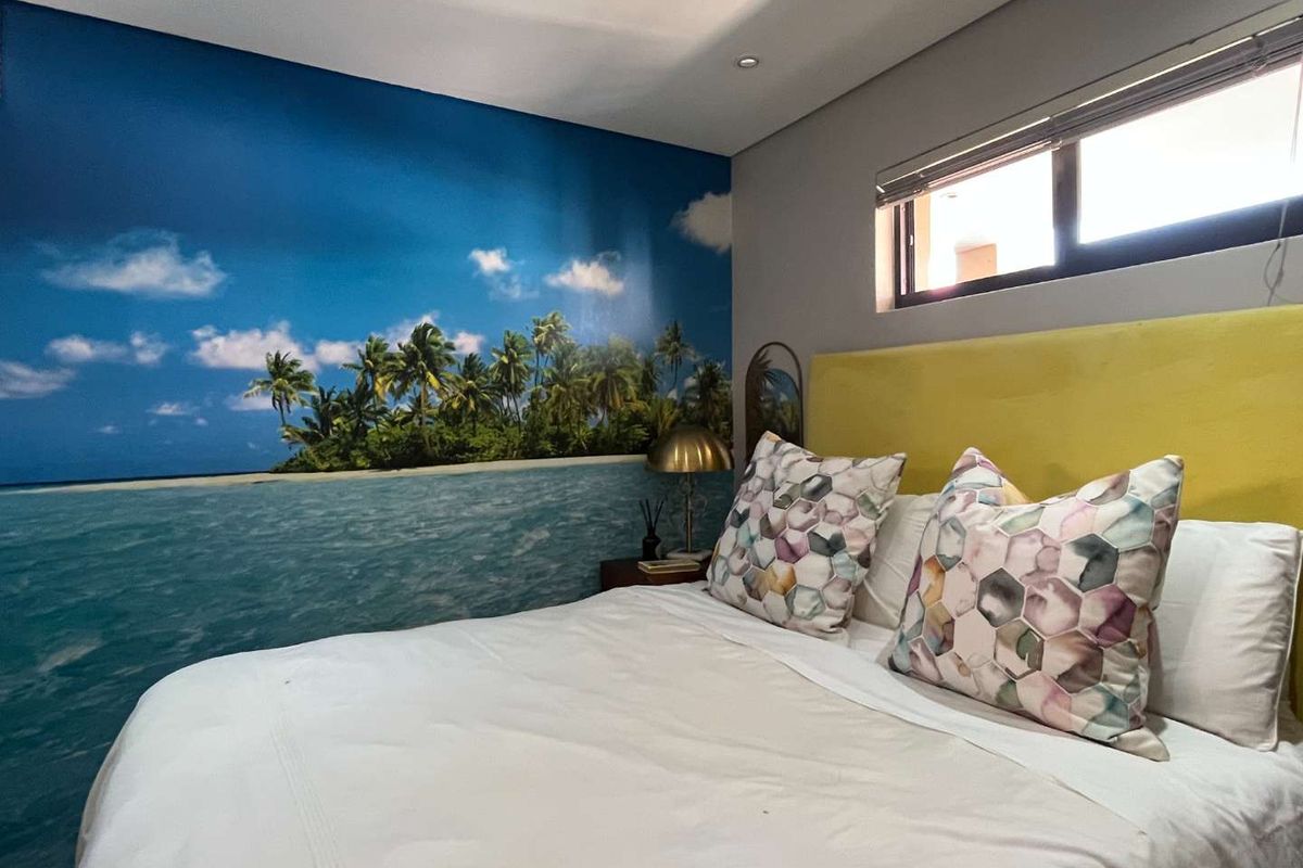 A bedroom featuring a large tropical mural feature wall, recessed ceiling lighting, and a high-level horizontal window.