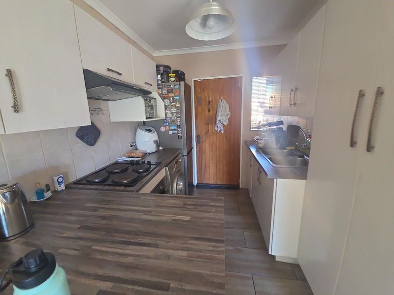 Functional galley-style kitchen featuring built-in cabinetry, laminate countertops, an electric hob with extractor fan, and tiled flooring.