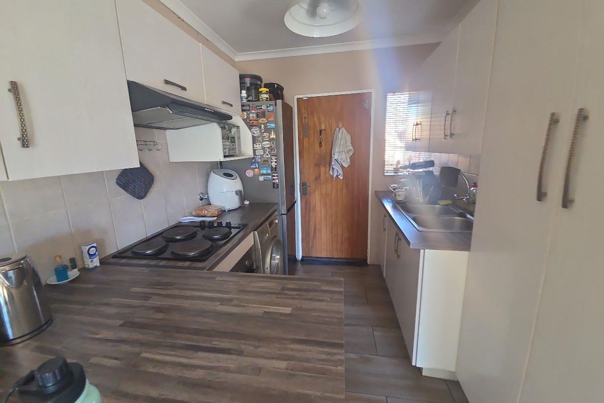 Functional galley-style kitchen featuring built-in cabinetry, laminate countertops, an electric hob with extractor fan, and tiled flooring.