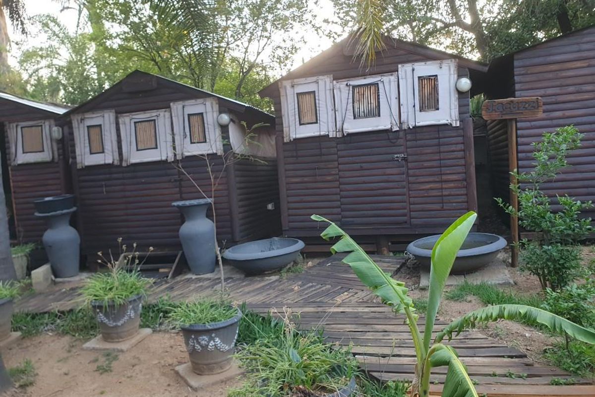 Exterior view of timber cottage structures featuring wooden decking and rustic garden landscaping.