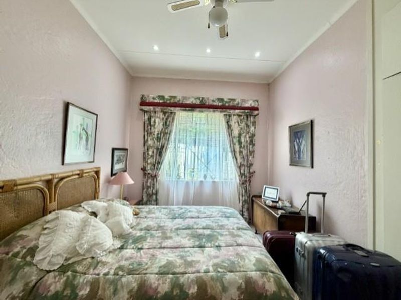 A bedroom featuring a ceiling fan, recessed lighting, and built-in storage, presented in a dated but functional condition.