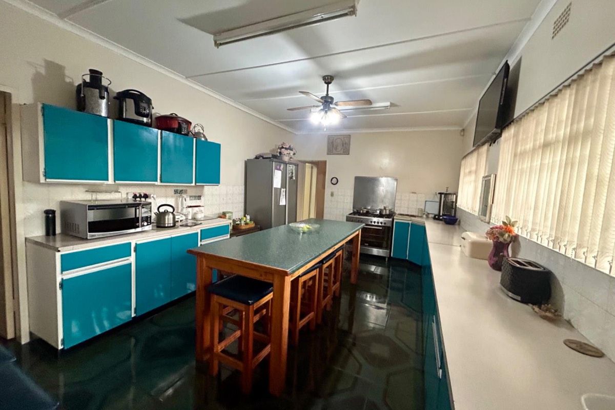 Spacious kitchen featuring teal cabinetry, a central island, tiled flooring, and a built-in stove with an extractor fan.