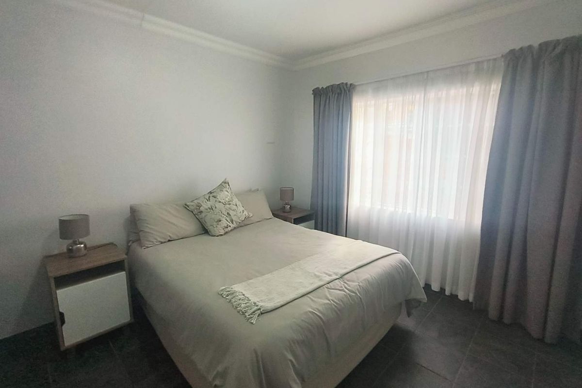 A well-lit bedroom featuring tiled flooring, neutral wall finishes, and window treatments, providing a comfortable and functional living space.