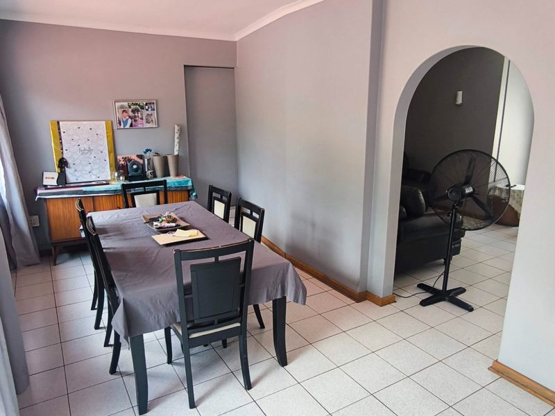 A dining room featuring tiled flooring and a distinctive arched doorway leading to an adjacent living space.