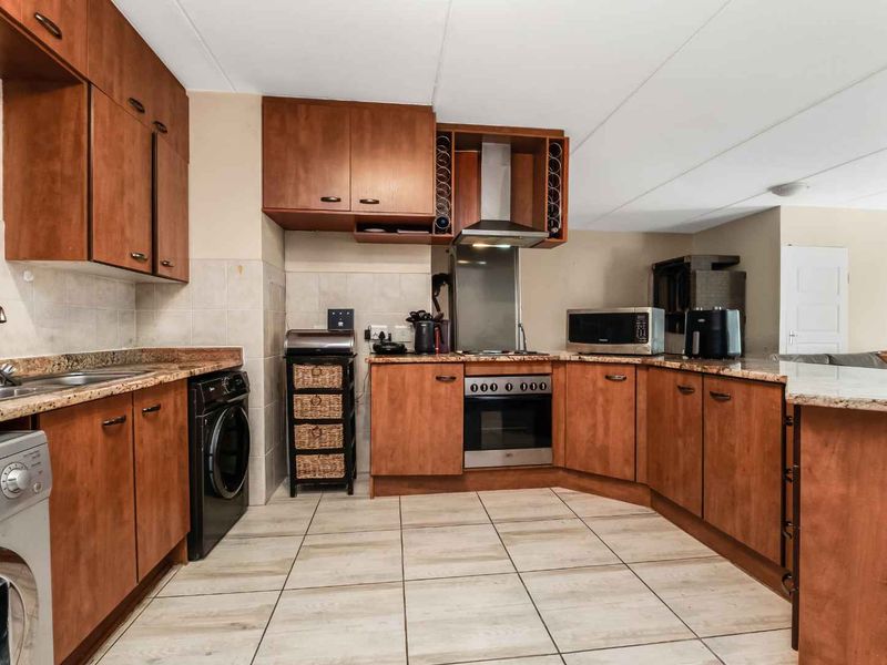 Functional kitchen featuring wooden cabinetry, granite countertops, tiled flooring, and built-in stainless steel appliances, offering a practical layout for daily cooking and preparation.