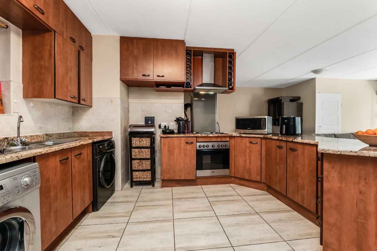 Functional kitchen featuring wooden cabinetry, granite countertops, tiled flooring, and built-in stainless steel appliances, offering a practical layout for daily cooking and preparation.