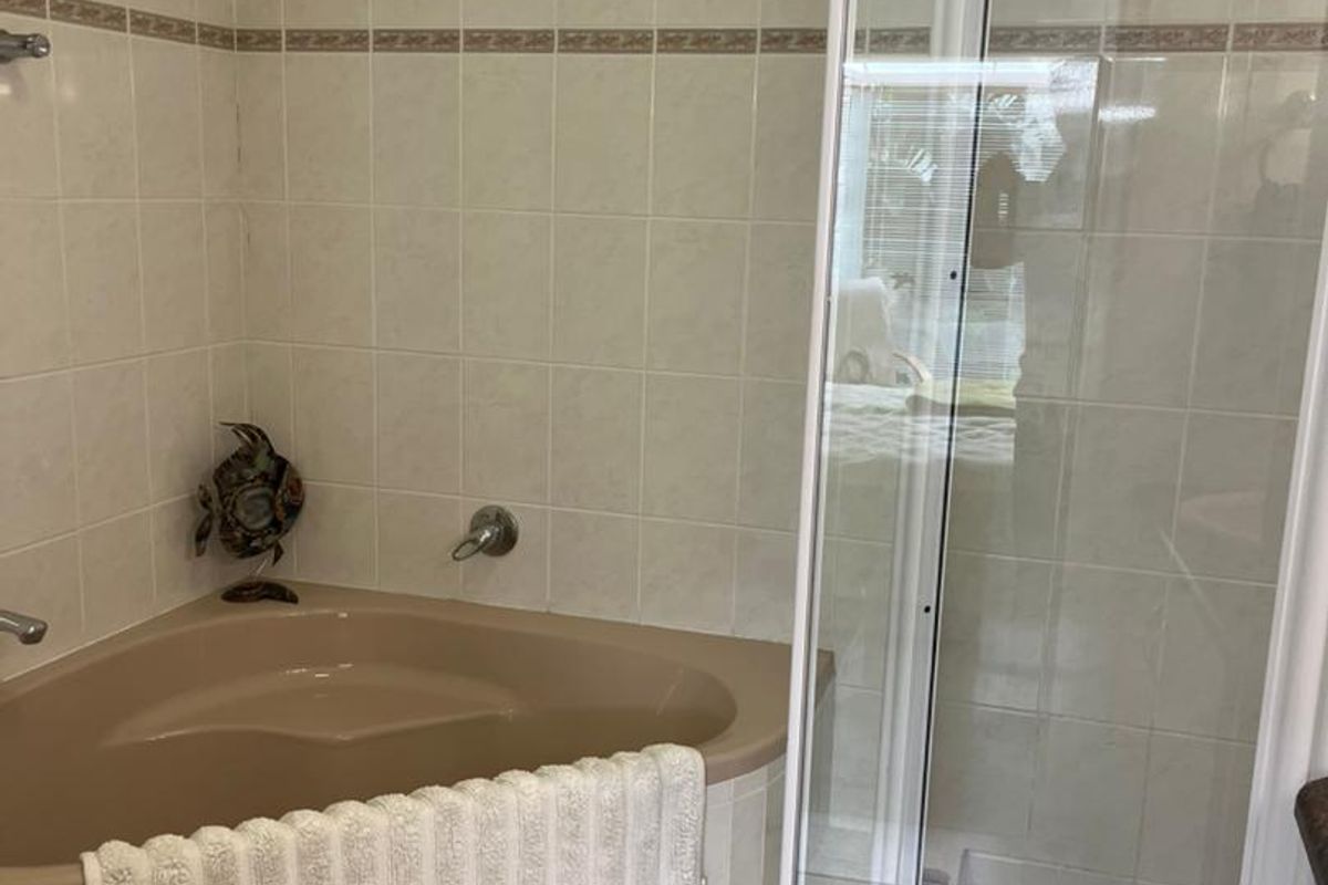 A bathroom featuring a corner bathtub with beige finish, a separate glass-enclosed shower, and neutral wall tiling.