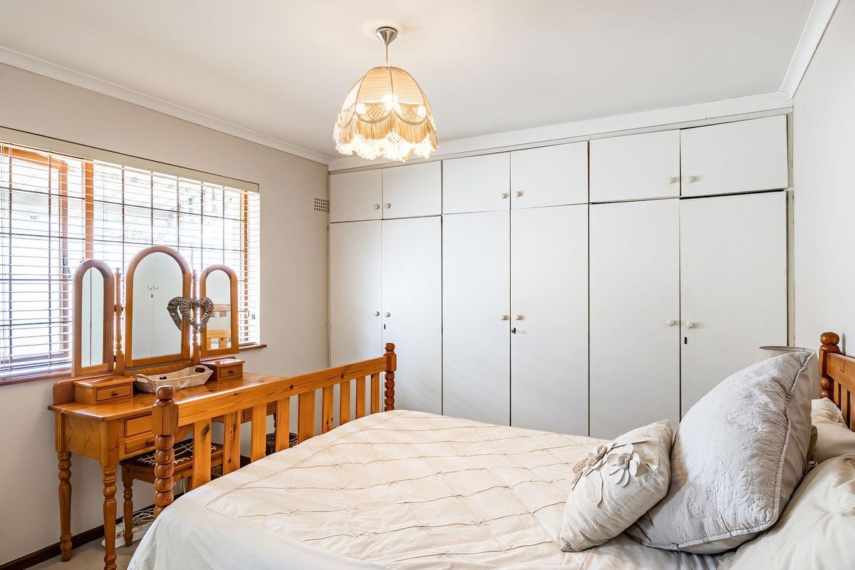A well-lit bedroom featuring extensive floor-to-ceiling built-in cabinetry and large windows with fitted blinds.