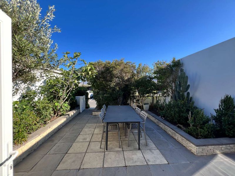 A well-maintained paved patio area featuring raised garden beds and a boundary wall, providing a private outdoor space for relaxation.