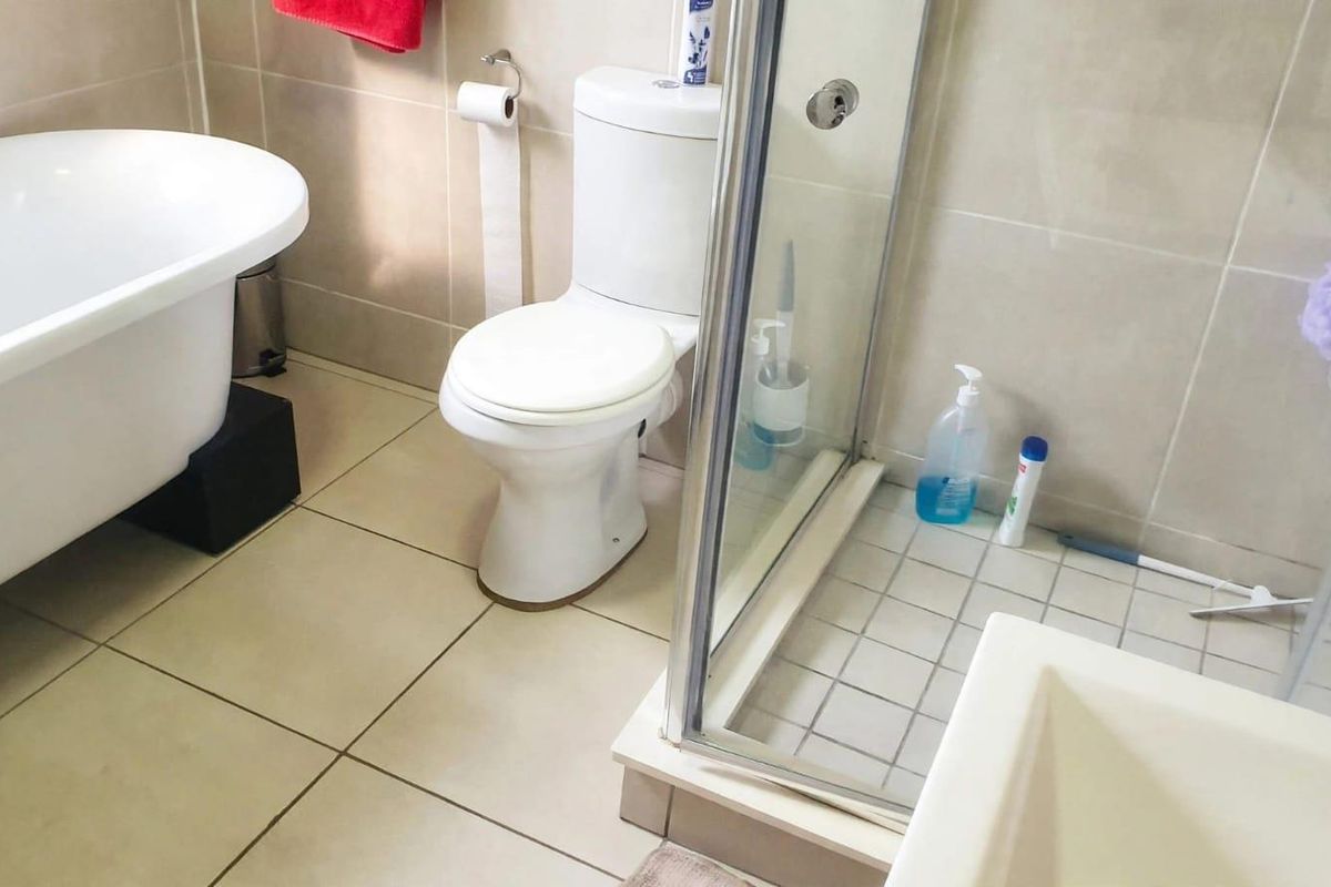 A functional bathroom featuring a freestanding bathtub, a separate glass-enclosed shower, and neutral wall and floor tiling.