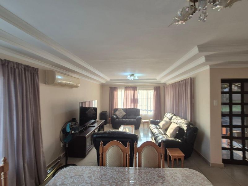 Spacious living room featuring tiled flooring, recessed ceiling detailing, and an integrated air conditioning unit, providing a comfortable and functional living space.
