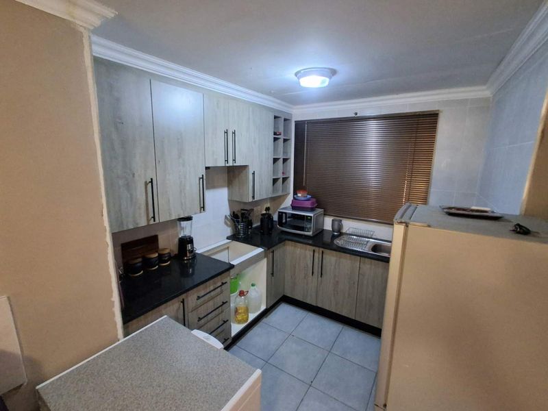 Compact kitchen featuring modern laminate cabinetry, granite countertops, tiled flooring, and a functional sink area with integrated storage.