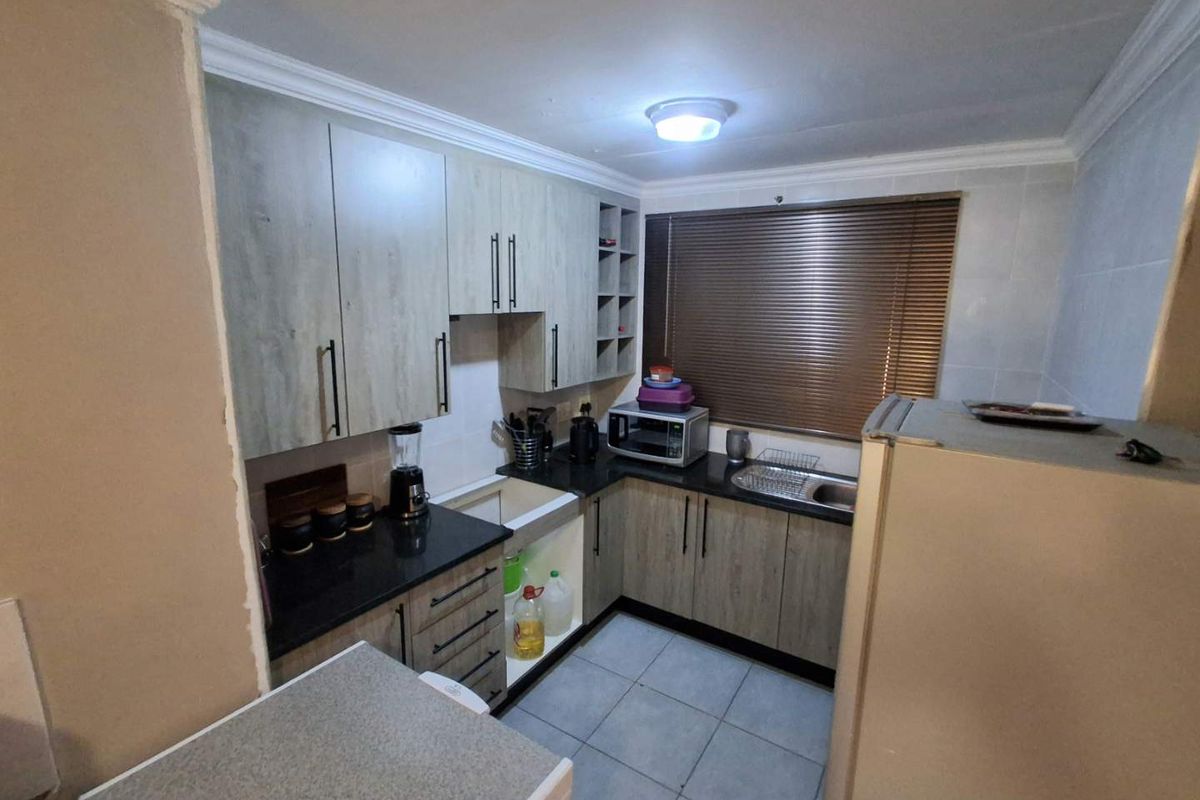 Compact kitchen featuring modern laminate cabinetry, granite countertops, tiled flooring, and a functional sink area with integrated storage.