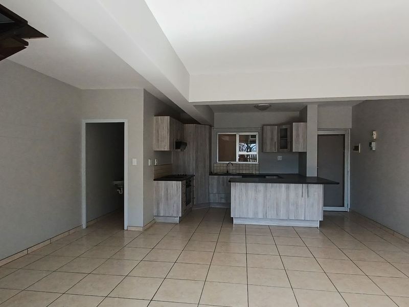 Spacious open-plan living area featuring a modern kitchen with built-in cabinetry, an island, and tiled flooring throughout.