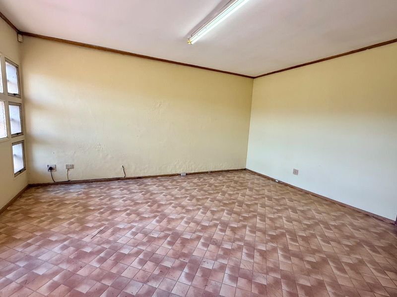 An empty office space featuring tiled flooring, fluorescent lighting, and multiple electrical outlets, ready for customization or professional fit-out.