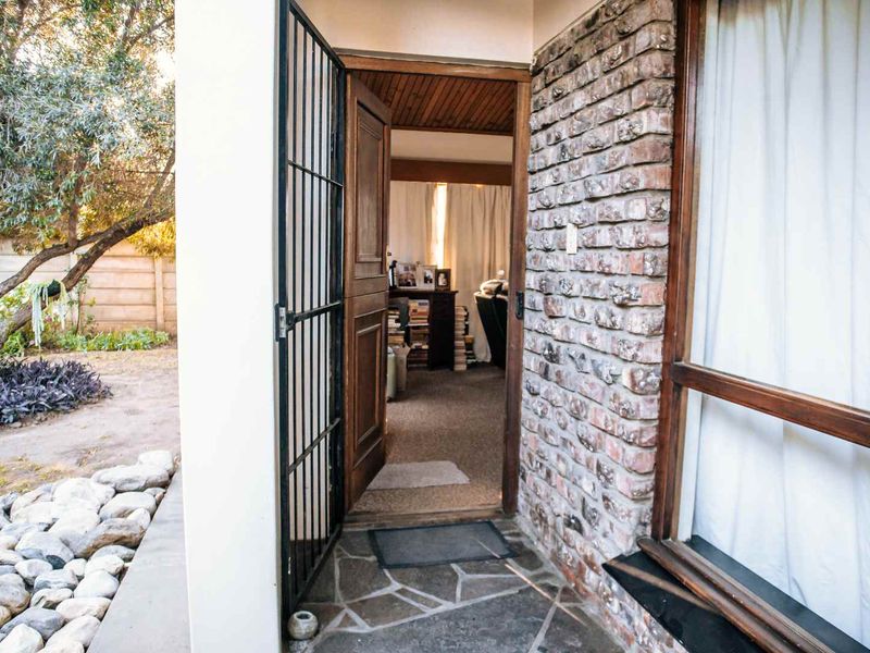 Entrance area featuring exposed brickwork, stone paving, and a secure timber door leading into the home interior.