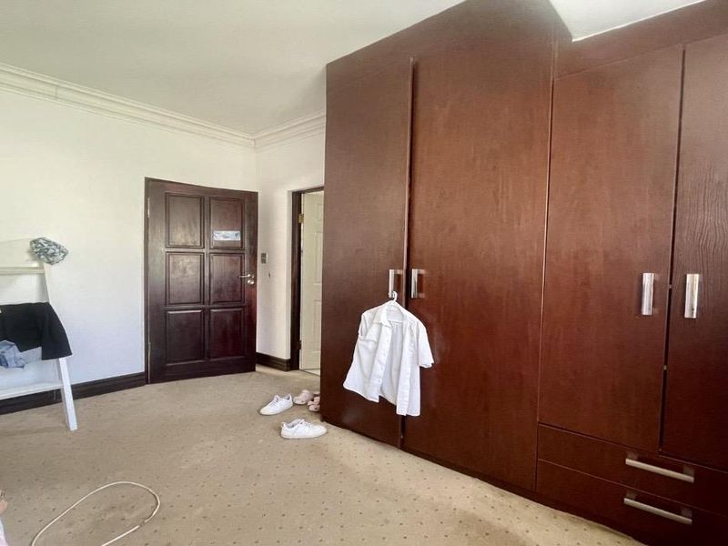 A bedroom featuring built-in wooden cupboards, carpeted flooring, and classic cornice detailing.