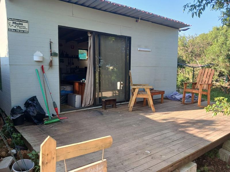 A timber deck patio attached to a residential structure with sliding glass door access and metal roofing.