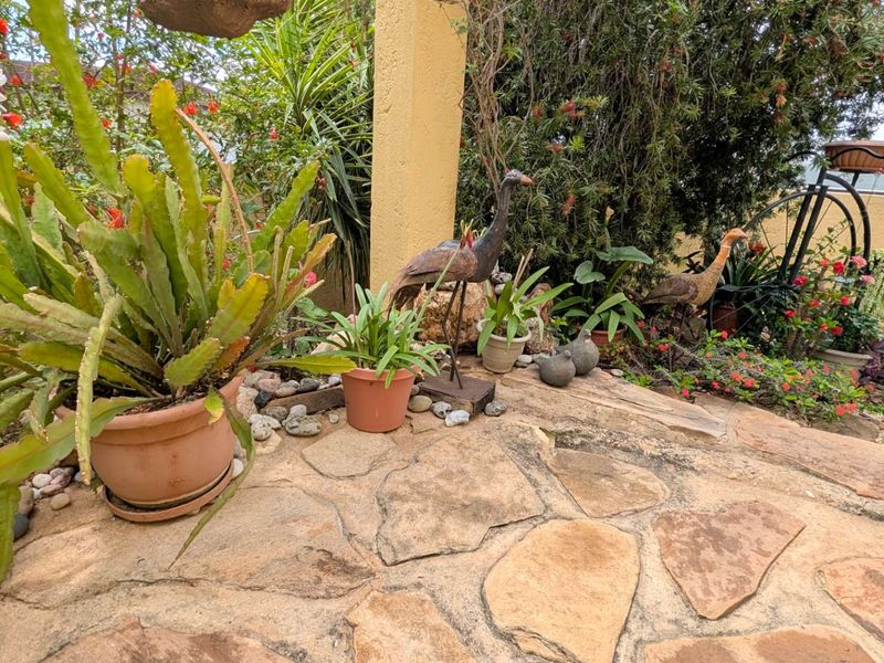 A landscaped garden area featuring natural stone paving, a boundary wall, and established greenery.