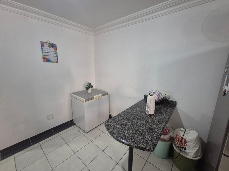 A functional laundry or utility space featuring ceramic floor tiles, a granite-topped prep counter, and coved ceiling detailing.