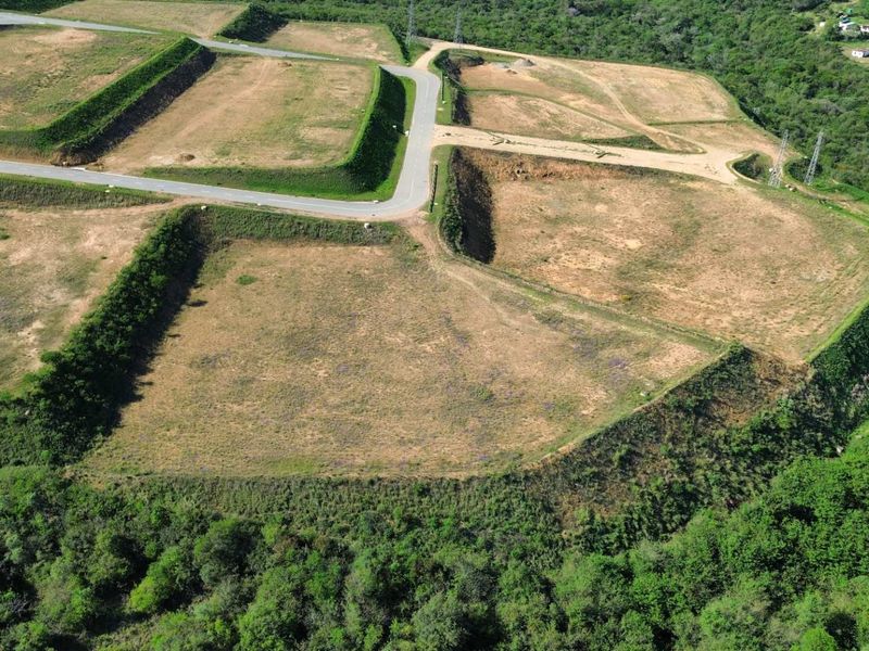 Aerial view of an industrial development site featuring terraced land plots, retaining embankments, and established paved access roads surrounded by natural vegetation.