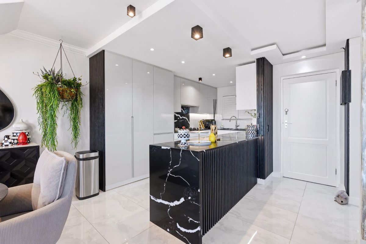 Modern kitchen featuring a striking black marble island, sleek high-gloss cabinetry, and polished porcelain floor tiles with contemporary recessed ceiling lighting.