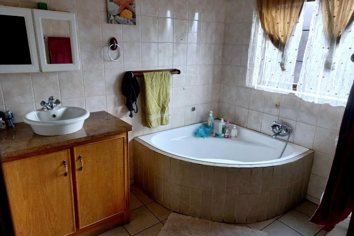 A dated bathroom featuring a corner bathtub, vanity cabinet with vessel sink, and tiled finishes throughout.