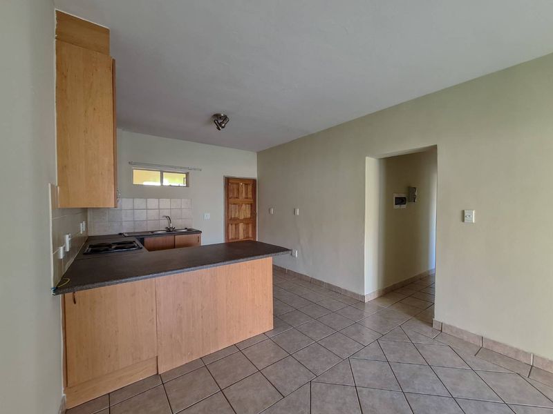 Open plan kitchen and living area featuring tiled floors, built-in cabinetry with laminate countertops, and a built-in hob.