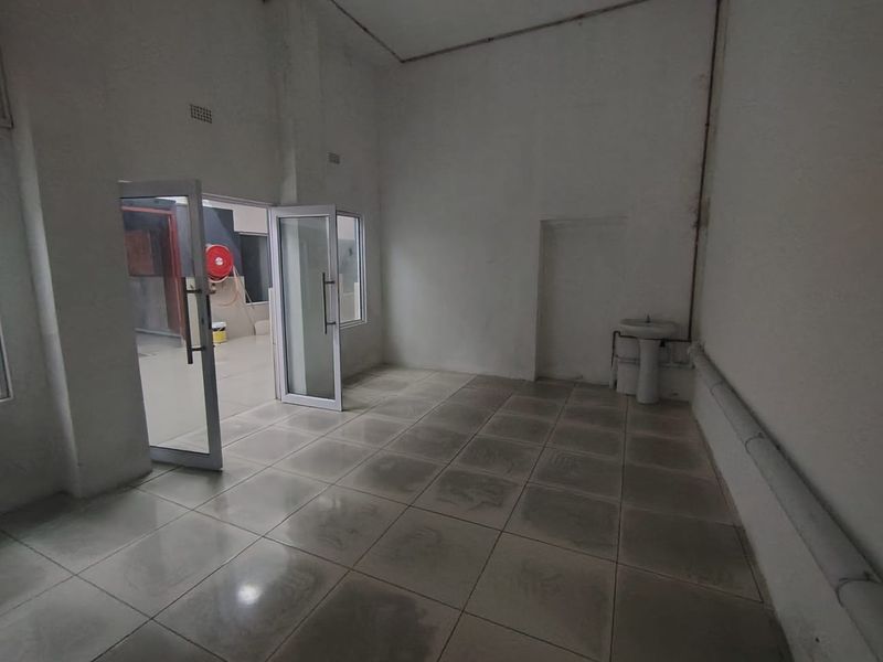 An empty utility space featuring tiled flooring, a pedestal basin, and an aluminium-framed glass door leading to an adjacent area.