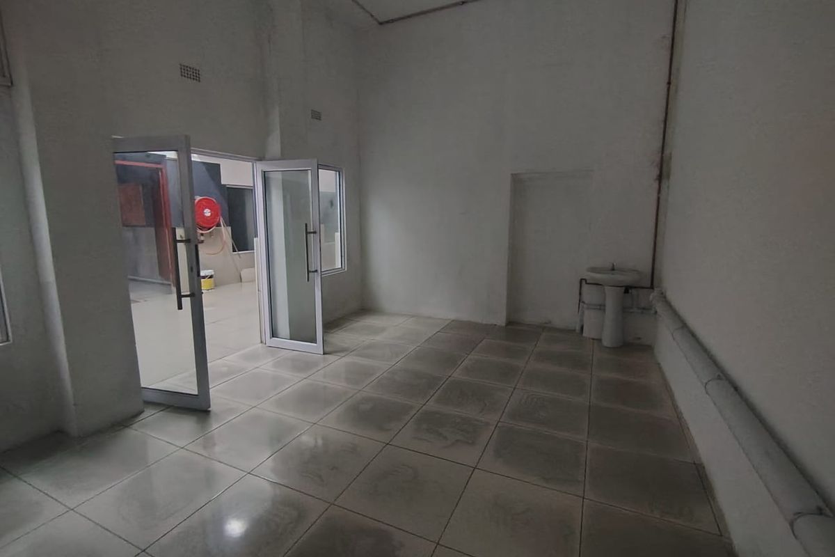 An empty utility space featuring tiled flooring, a pedestal basin, and an aluminium-framed glass door leading to an adjacent area.