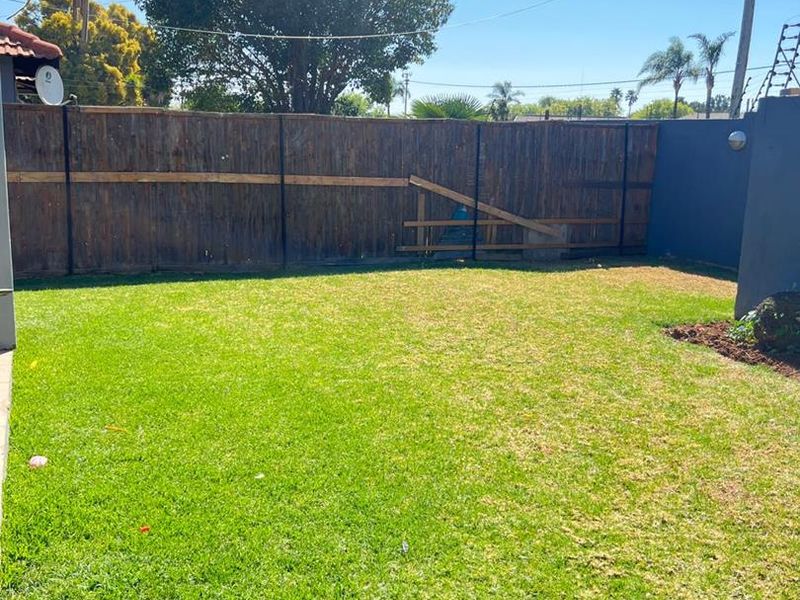 A private backyard featuring a well-maintained lawn and perimeter timber fencing, offering a clear outdoor space for potential landscaping or recreational use.
