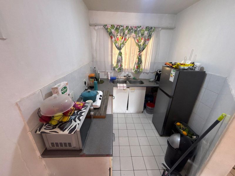 A compact kitchen featuring tiled flooring, a double basin sink, and built-in cabinetry with a tiled splashback.