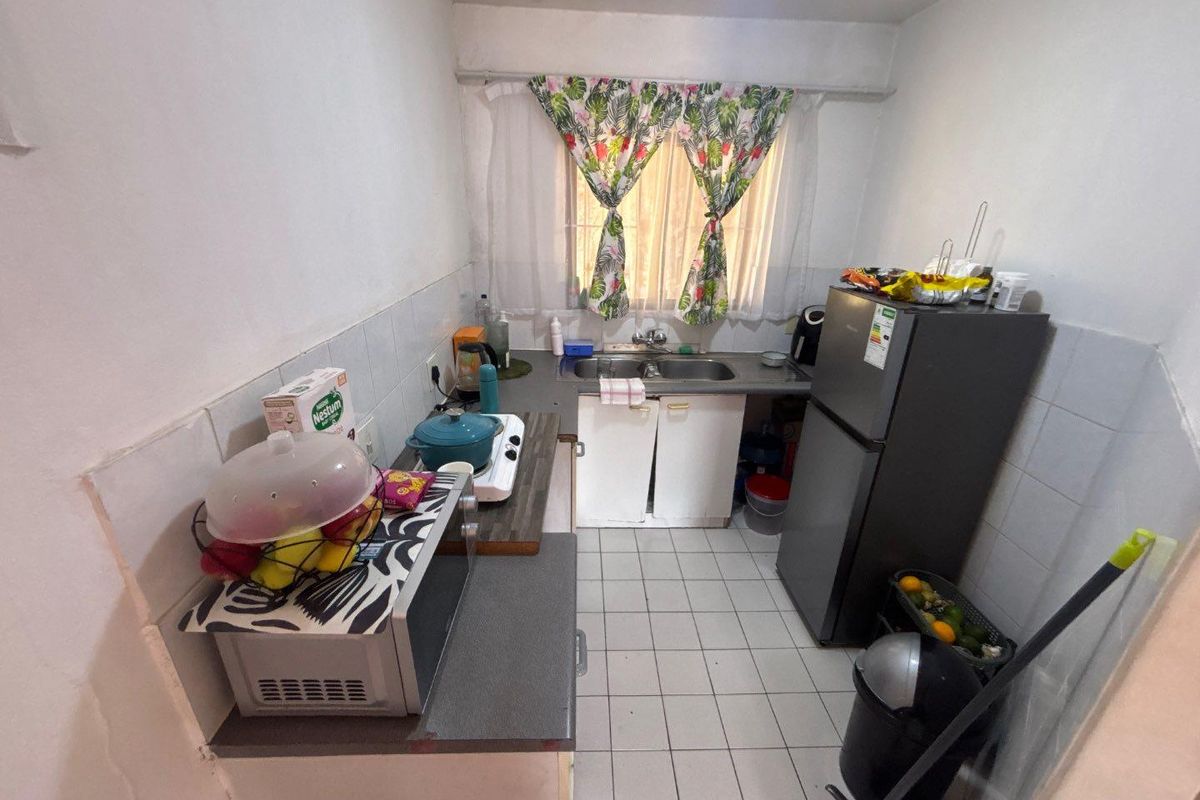 A compact kitchen featuring tiled flooring, a double basin sink, and built-in cabinetry with a tiled splashback.
