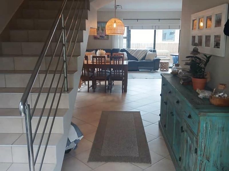 Open plan living and dining area featuring tiled flooring and a modern staircase with a stainless steel balustrade.