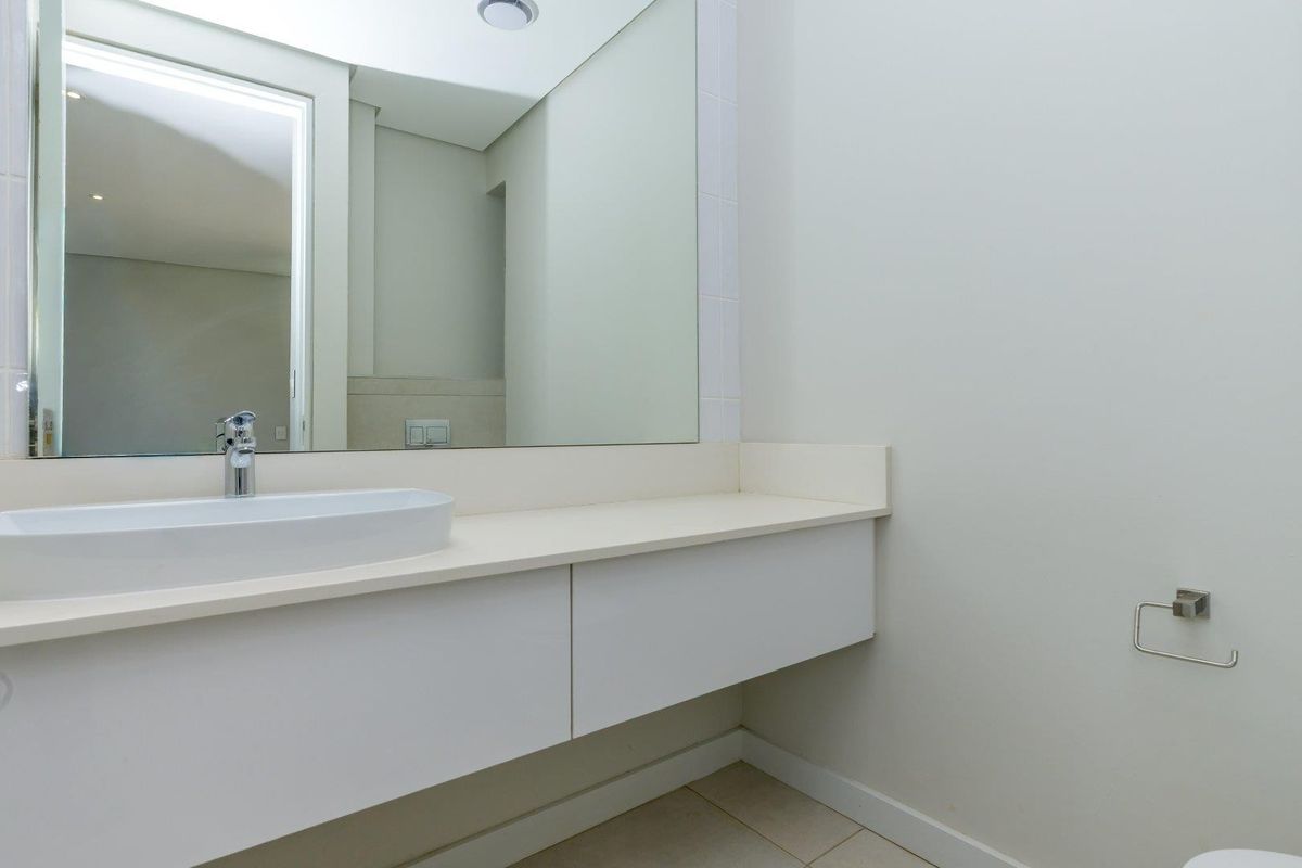 A clean and modern bathroom featuring a wall-mounted vanity with a vessel sink, large mirror, and minimalist chrome fixtures.