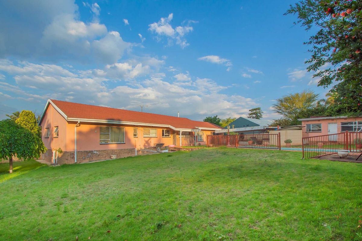 Rear view of the house featuring a spacious lawn, swimming pool area, and traditional tiled roof architecture.