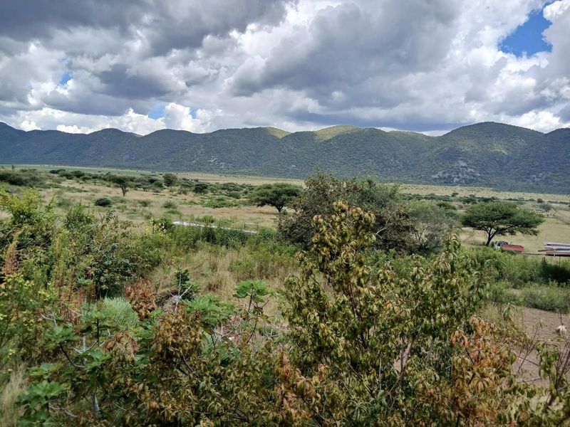A scenic landscape view of the farm property featuring expansive open fields and rolling mountains in the background.