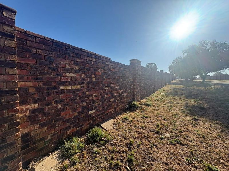 A sturdy, well-maintained face-brick boundary wall with integrated pillars, providing secure perimeter definition for the residential property.