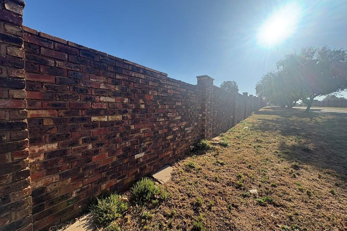 A sturdy, well-maintained face-brick boundary wall with integrated pillars, providing secure perimeter definition for the residential property.