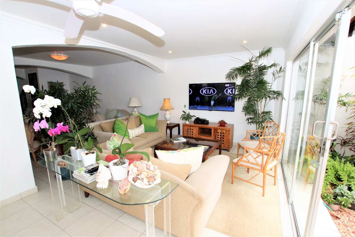 A bright living room featuring tiled flooring, a ceiling fan, and large sliding glass doors that provide access to an outdoor area.