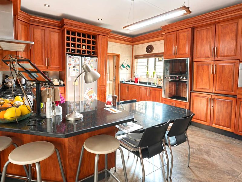 Spacious kitchen featuring extensive wooden cabinetry, granite countertops, built-in appliances, and a central island with integrated seating.