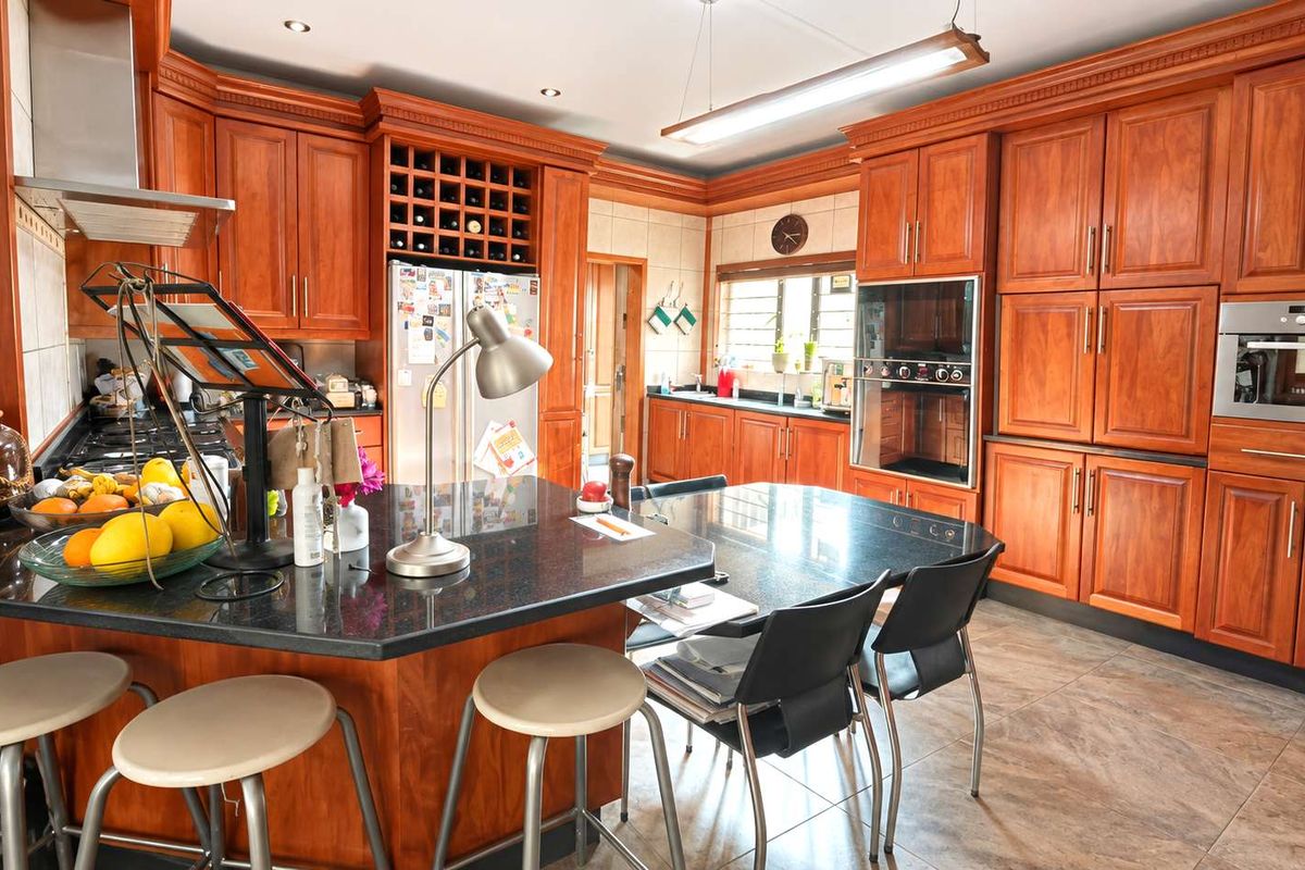 Spacious kitchen featuring extensive wooden cabinetry, granite countertops, built-in appliances, and a central island with integrated seating.